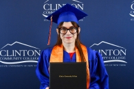 A graduate holding their diploma