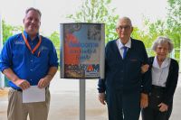 Three people standing next to a sign that says 'Welcome Ken Knelly and family"