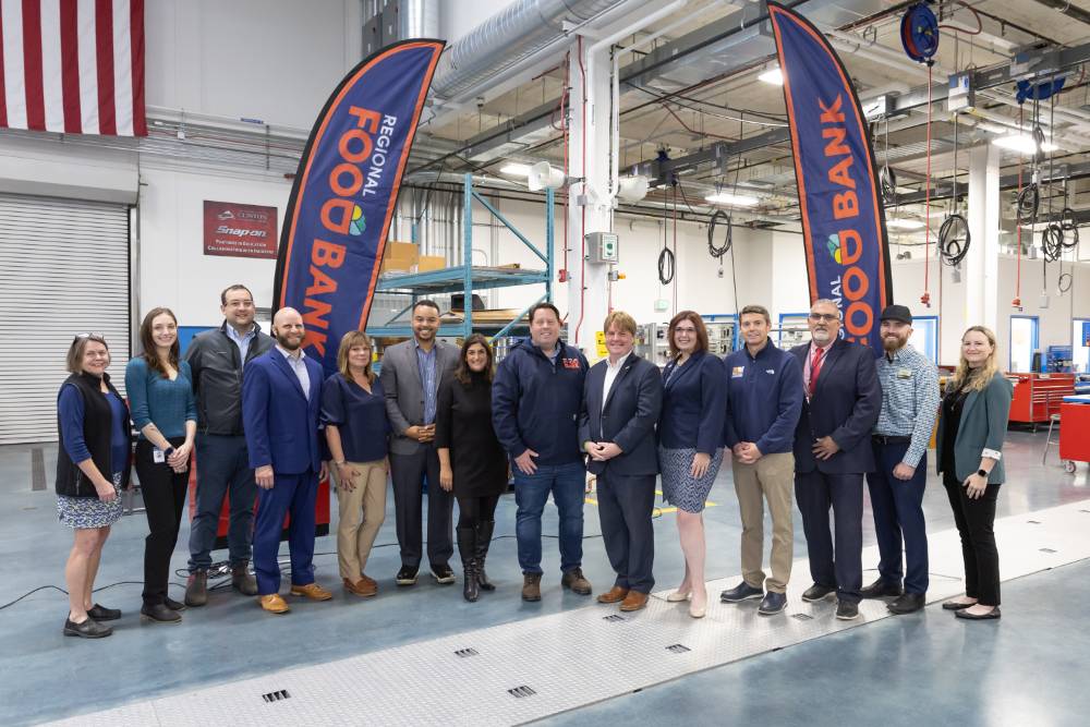 Several people standing side-by-side next to banners that say 'Regional Food Bank'