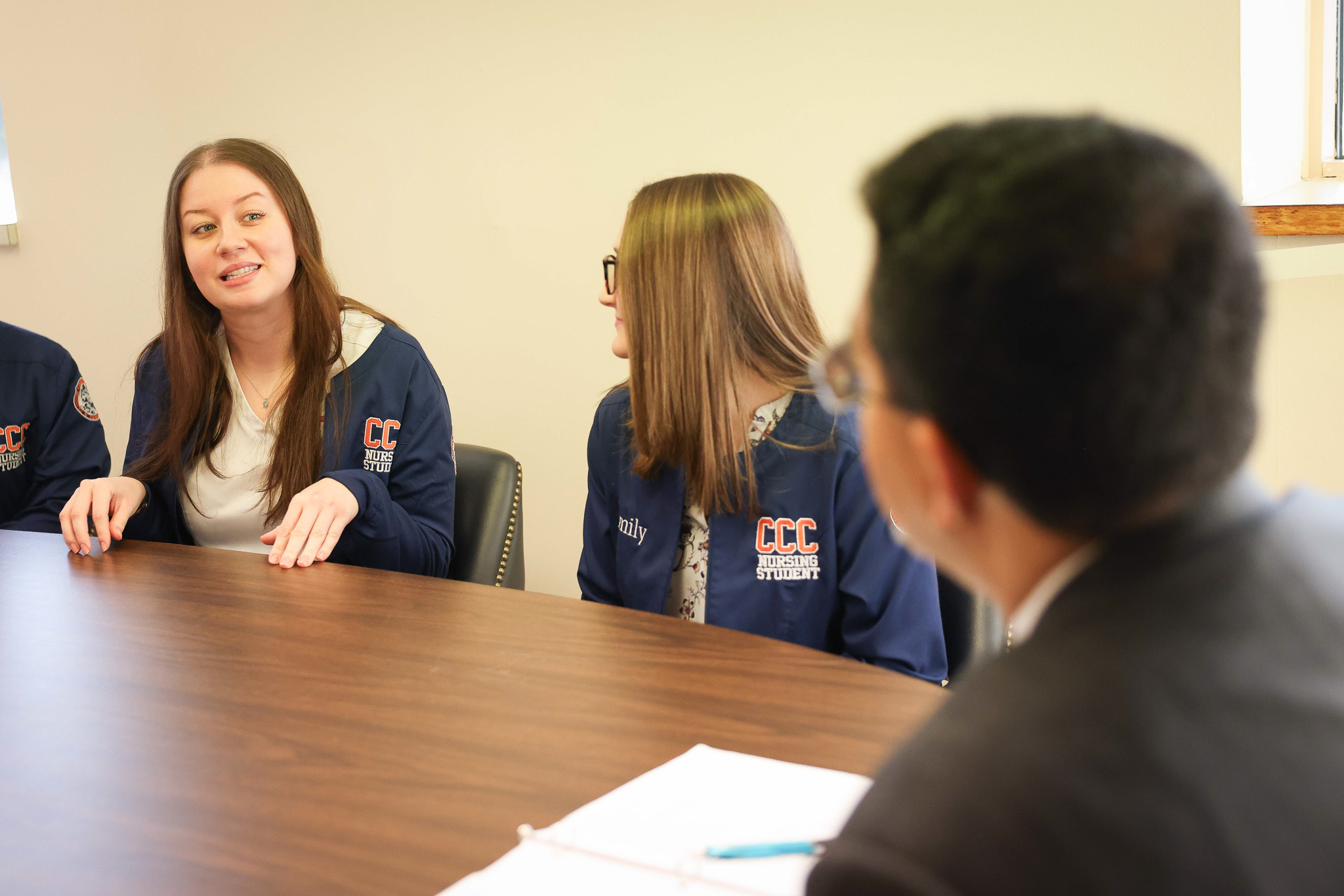 Two students sitting at a table speaking to a person
